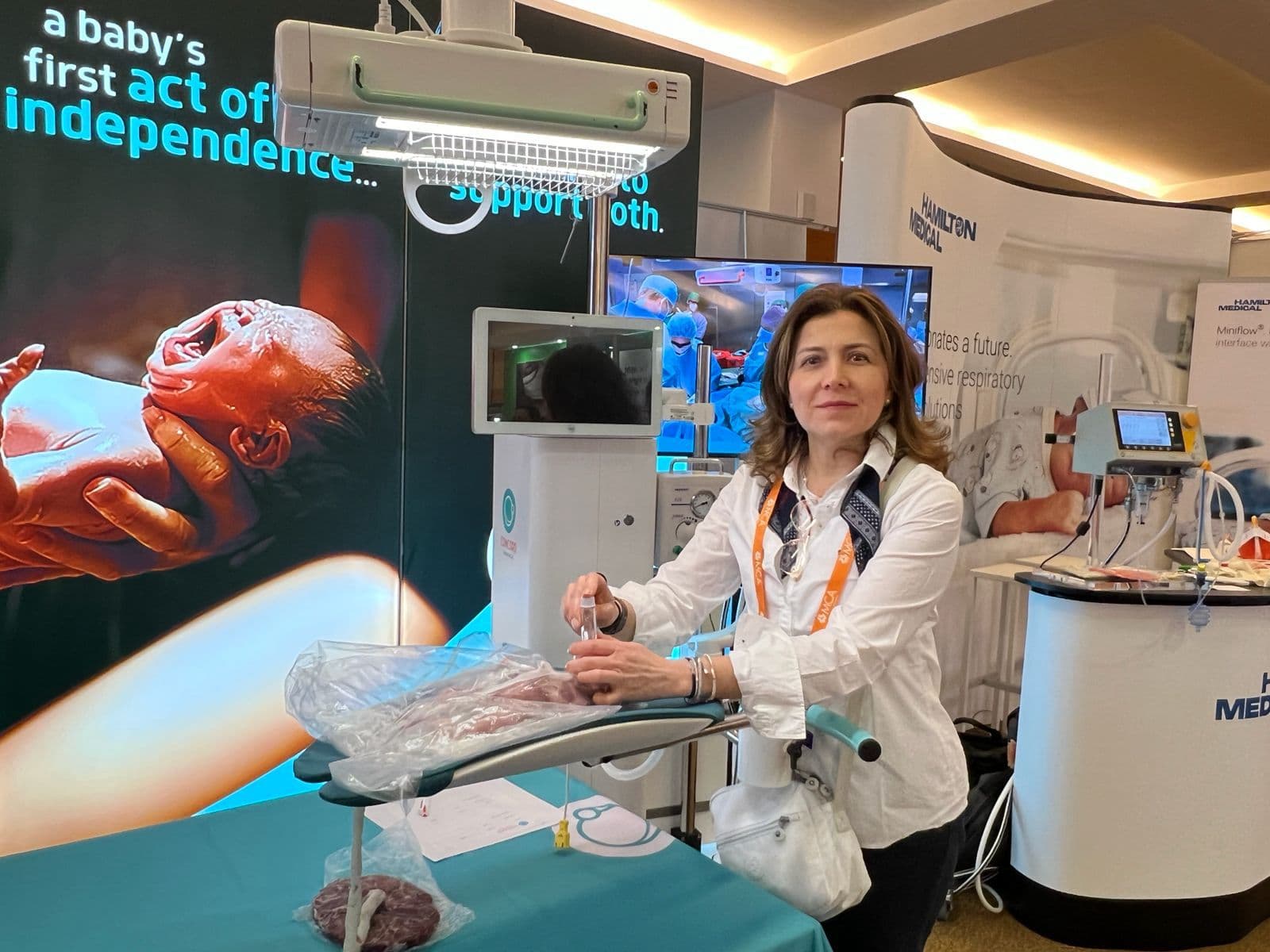 Dra. Marcela Castellanos en un congreso de neonatología junto a equipamiento de neuroprotección y monitorización neonatal
